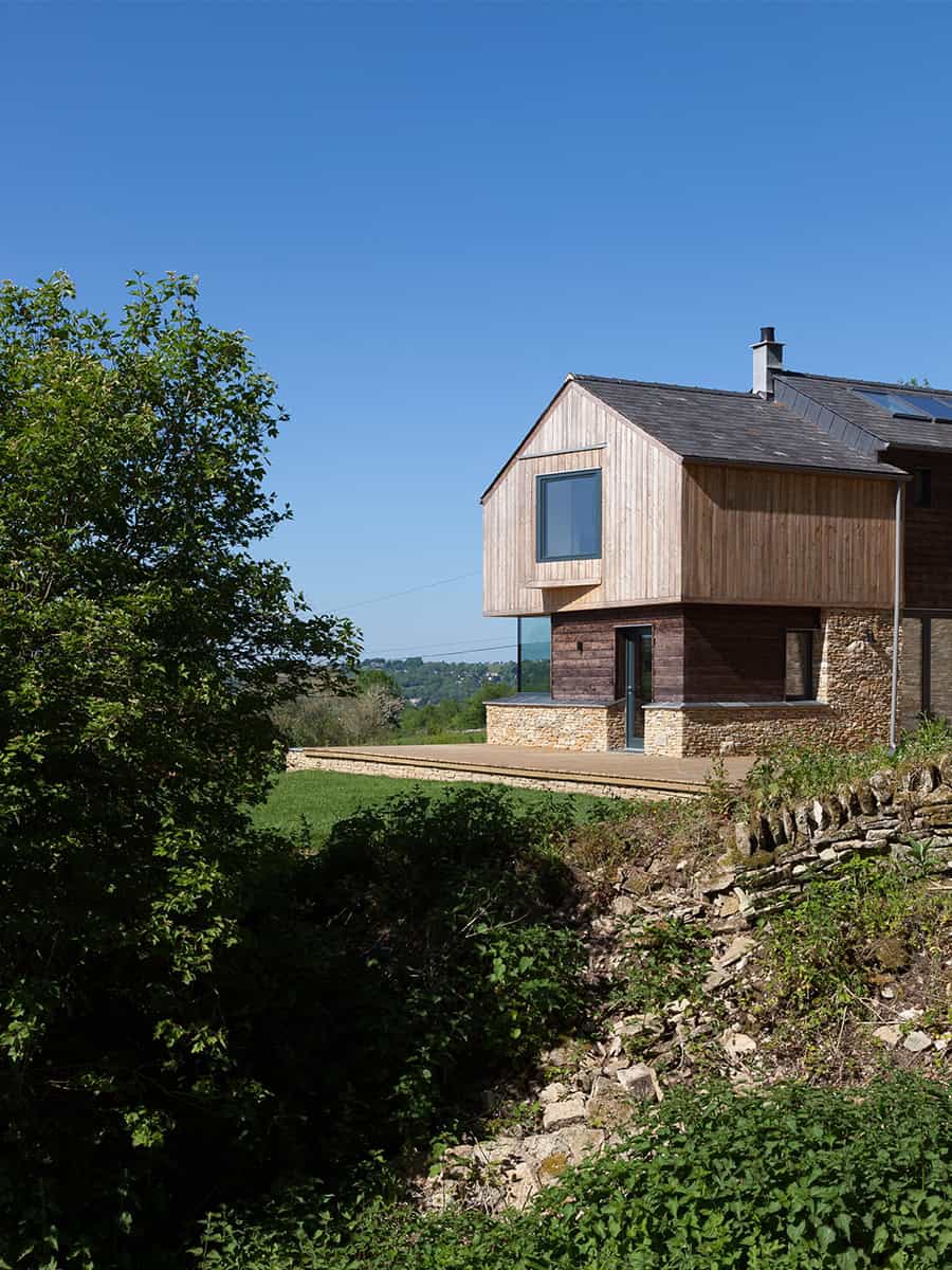 The Larch House on its Gloucestershire hillside with larch cladding, stone walls and valley views